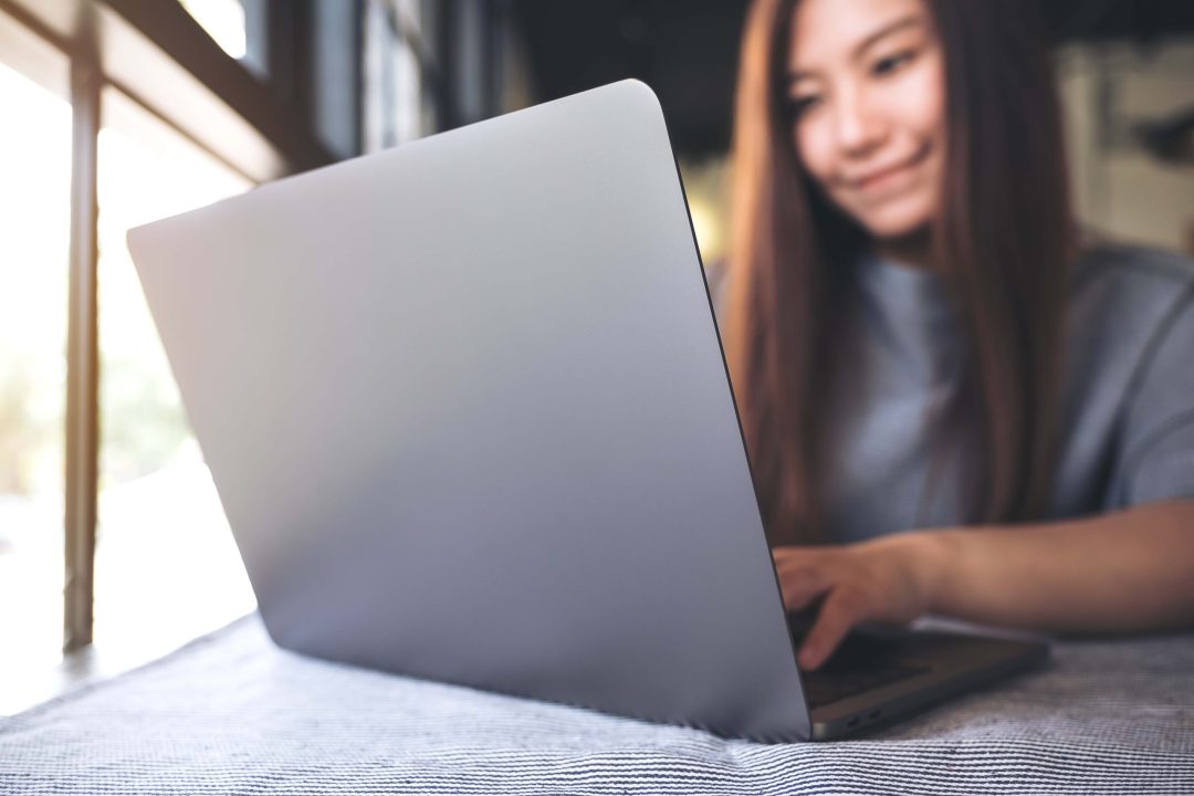 a-beautiful-asian-woman-working-and-typing-on-lapt-2022-12-16-05-01-46-utc